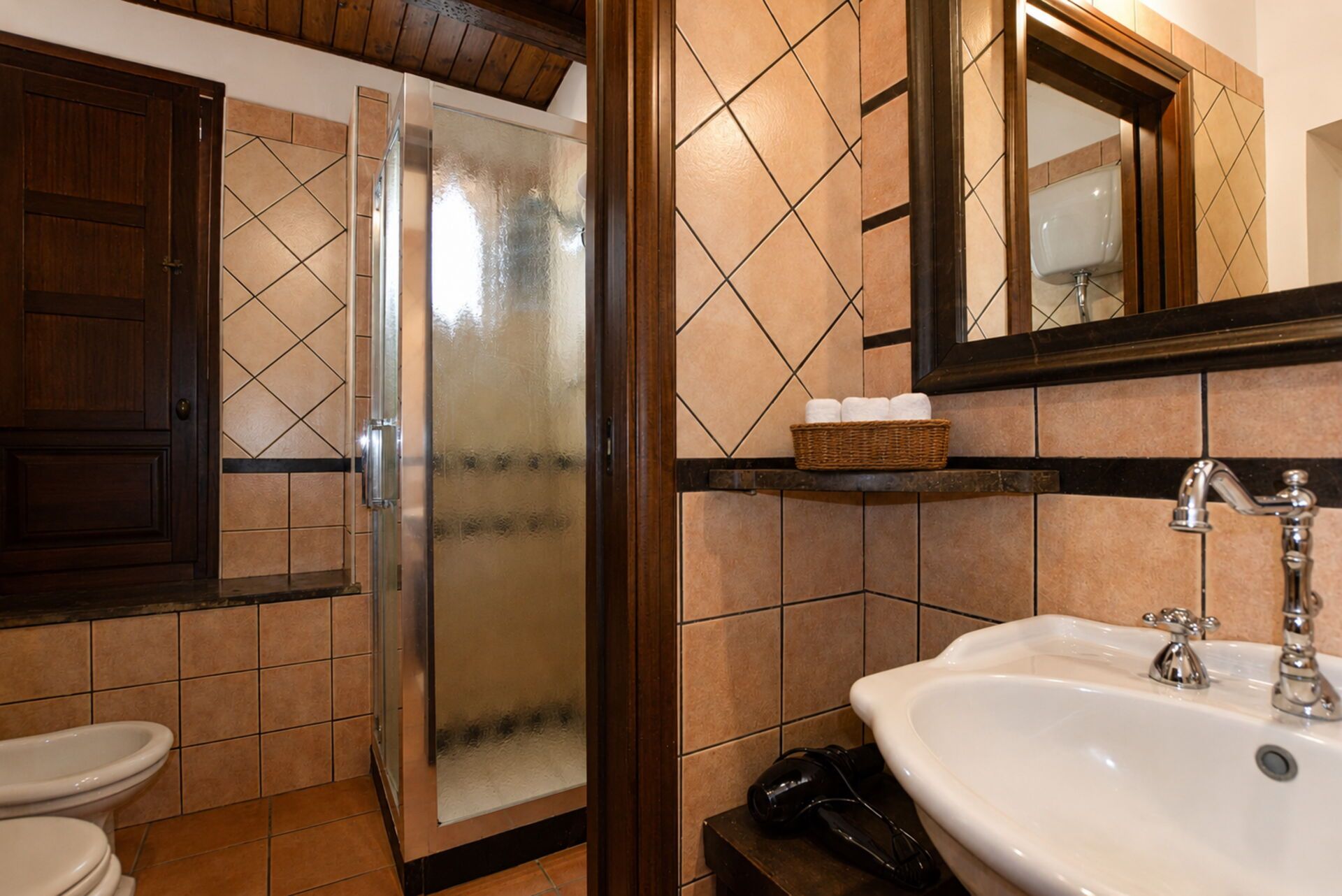 A bathroom with a shower, toilet, sink, and a mirror.