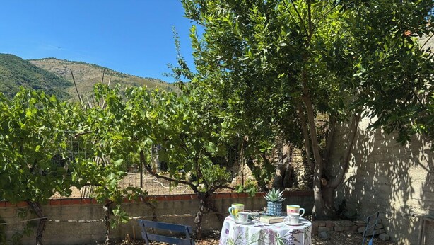A table set outdoors with chairs, surrounded by trees and a mountainous backdrop. - Il Fienile, Garden and Peacefull View (Arnasco)