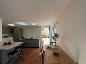Eine moderne Küche mit Essbereich, einem Holztisch und Blick ins Freie.