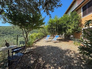 A patio with a table and chairs, a gravel path, and a view of a vineyard. - Il Fienile, Garden and Peacefull View (Arnasco)