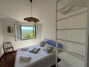 A bedroom with a bed, a window, a hanging light fixture, and a chair. - Il Fienile, Garden and Peacefull View (Arnasco)