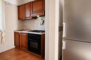 A kitchen with wooden cabinets, a stainless steel refrigerator, a gas stove, and a dishwasher. - Villa in Arenella with 2 bedrooms sleeps 5 (Arenella)