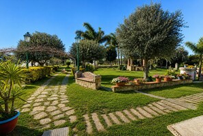 A garden with a stone pathway, a bench, and various plants. - Villa in Arenella with 2 bedrooms sleeps 5 (Arenella)