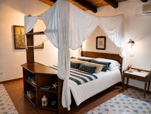 A bedroom with a canopy bed, wooden headboard, bedside tables, a nightstand, a lamp, a framed picture, and a bookshelf. - Villa in Arenella with 2 bedrooms sleeps 5 (Arenella)