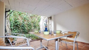 An outdoor patio with a table and chairs, surrounded by a garden view. - Newly renovated three-story 16th-century house in central Ceret (Céret)