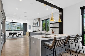 Una cocina moderna con una isla central, taburetes de bar e iluminación colgante.