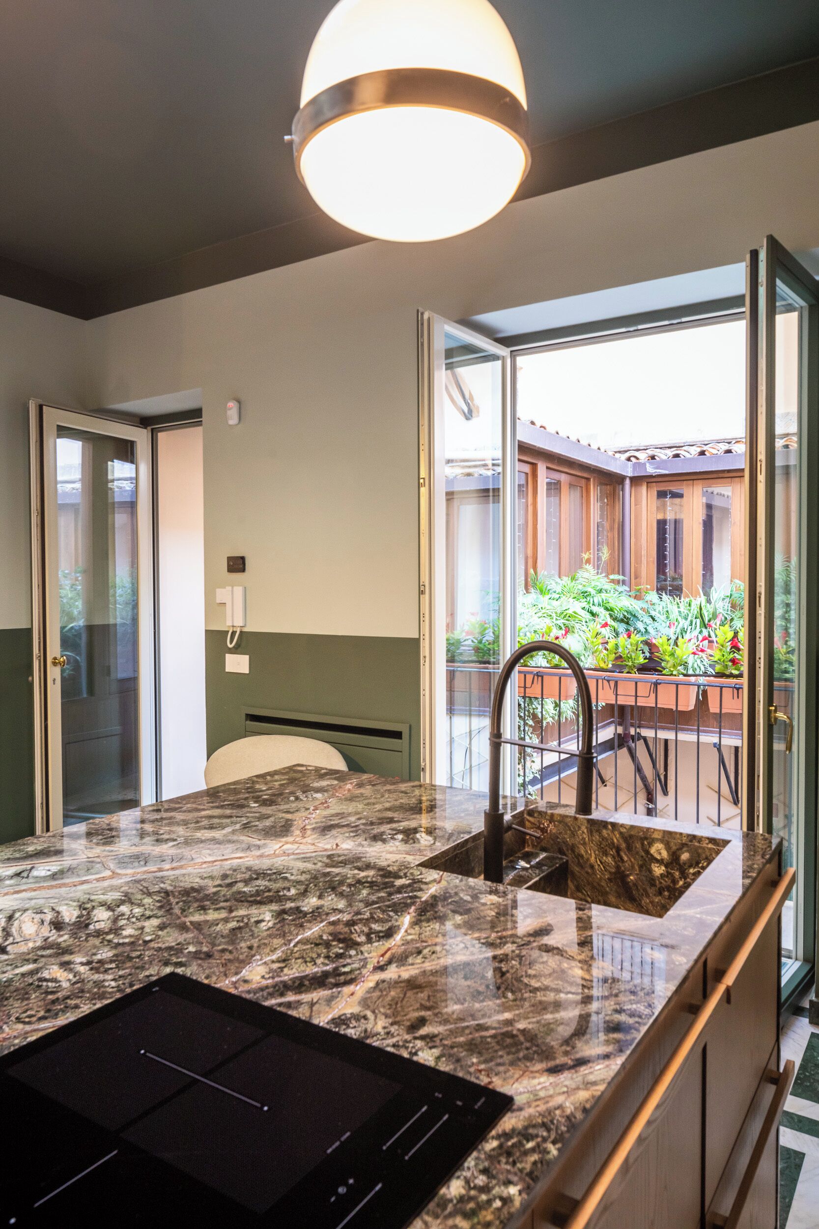 A kitchen with a marble countertop, a built-in stove, and a view of a balcony with plants.