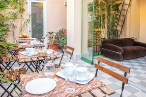 An outdoor dining area with tables set for two, chairs, and potted plants. - Le stanze al genio di Darlon (Palermo)