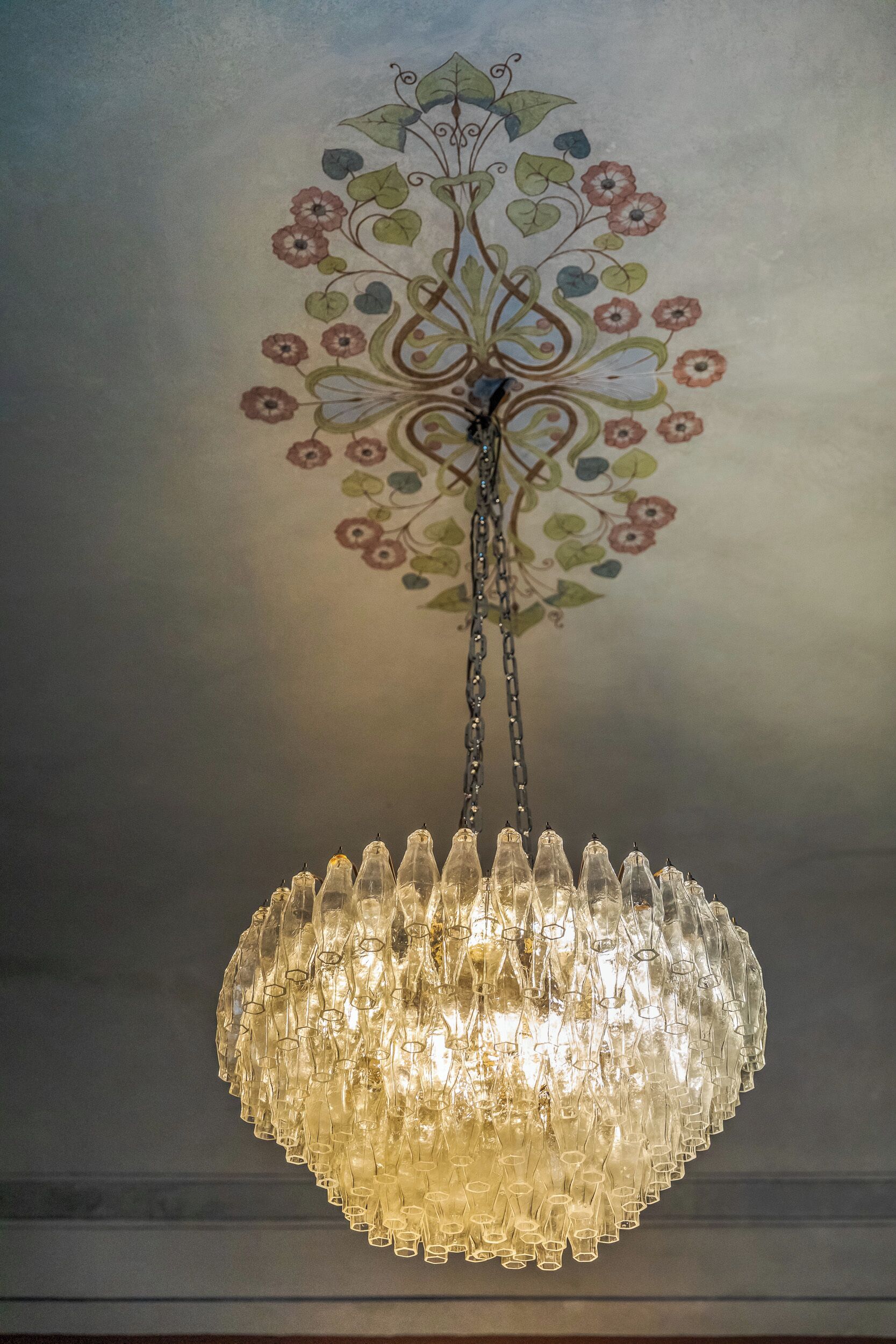 A chandelier with a floral design on the ceiling.