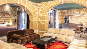 A modern living room with stone walls, a sofa set, a coffee table, and a kitchen area with an oven.