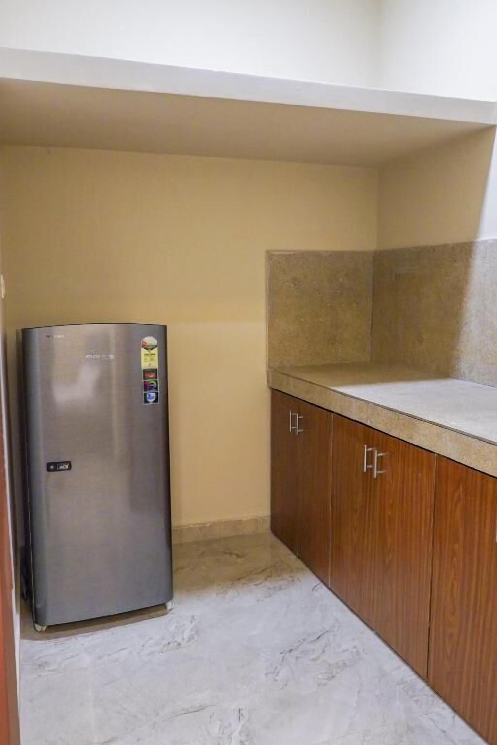 Una cocina con refrigerador de acero inoxidable, armarios de madera y encimera de mármol.