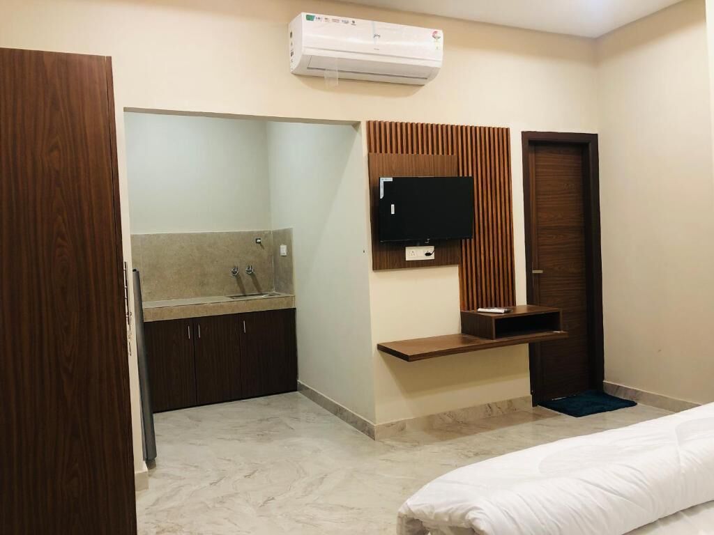 Habitación de hotel con cama, televisión montada en la pared, escritorio empotrado y armario.