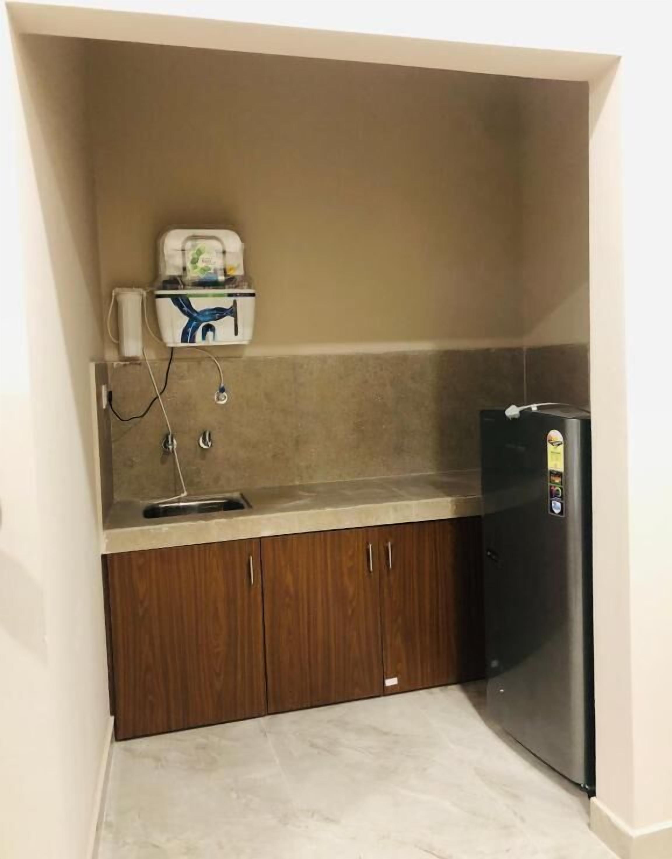 Una cucina compatta con frigorifero integrato, lavello e mobili in legno.