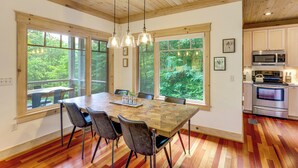 Una cocina amplia con ventanas grandes, una mesa de comedor con sillas y electrodomésticos modernos.