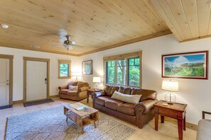 A living room with a wooden ceiling, leather sofas, a coffee table, a lamp, and a painting on the wall. - Spacious Home w/ Hot Tub & Views in Black Mountain (Black Mountain)