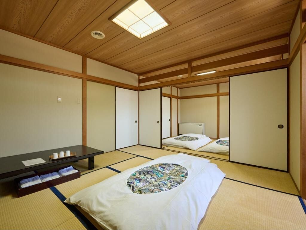 A traditional Japanese room with tatami flooring, a low wooden ceiling, and sliding doors.