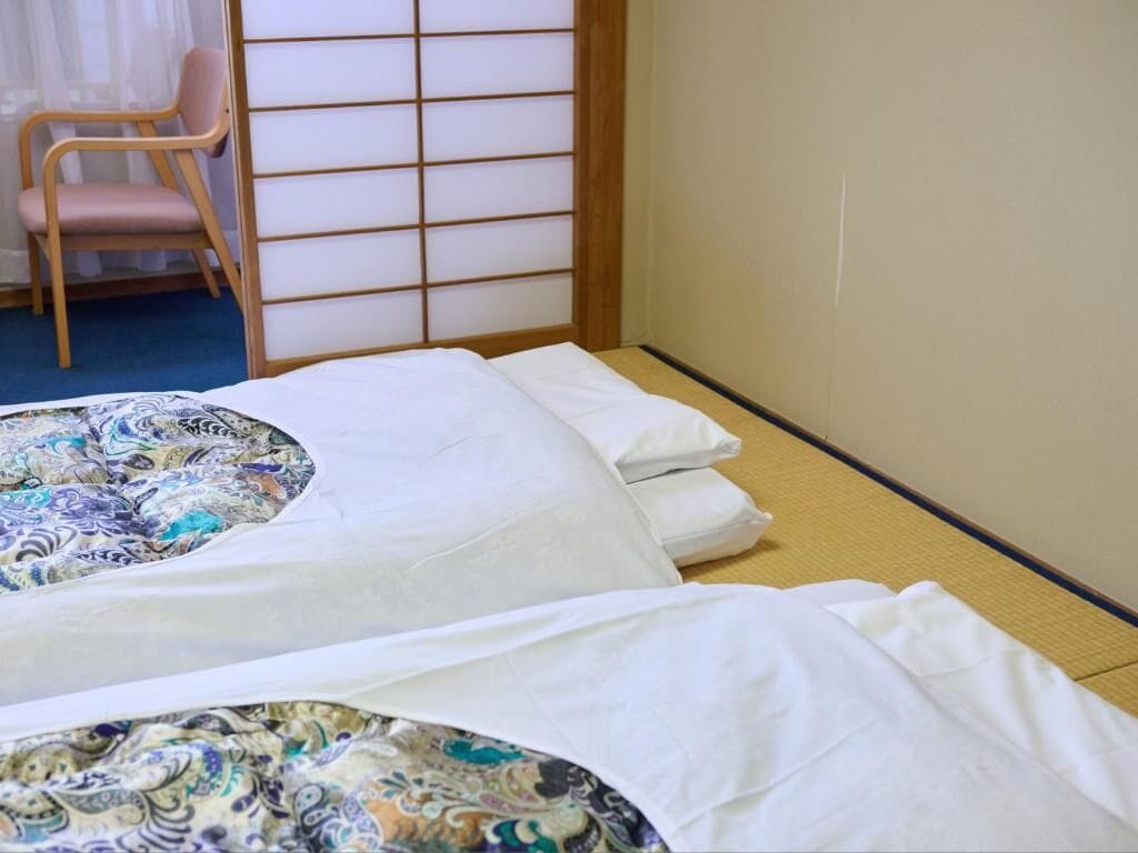A room with two beds, a chair, and a shoji screen.