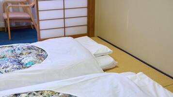 A room with two beds, a chair, and a shoji screen.