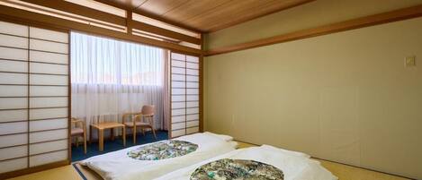A traditional Japanese room with tatami flooring, a shoji screen, and a futon bed with a patterned blanket.