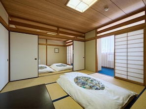 Una habitación japonesa tradicional con suelo de tatami, puertas correderas y una cama con almohada estampada.