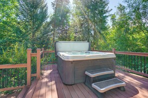 Ein Whirlpool auf einer Holzterrasse, umgeben von Bäumen.