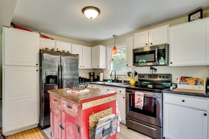 A kitchen with white cabinets, stainless steel appliances, a wooden island, and a hanging pendant light. - Welcome to Buck's Hideout in Bridgton Maine! (Bridgton)