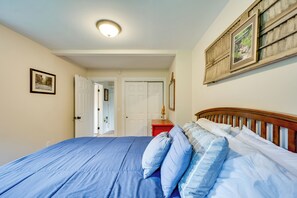 Une chambre à coucher comprenant un lit, une table de chevet, une commode et une porte donnant sur une autre pièce.