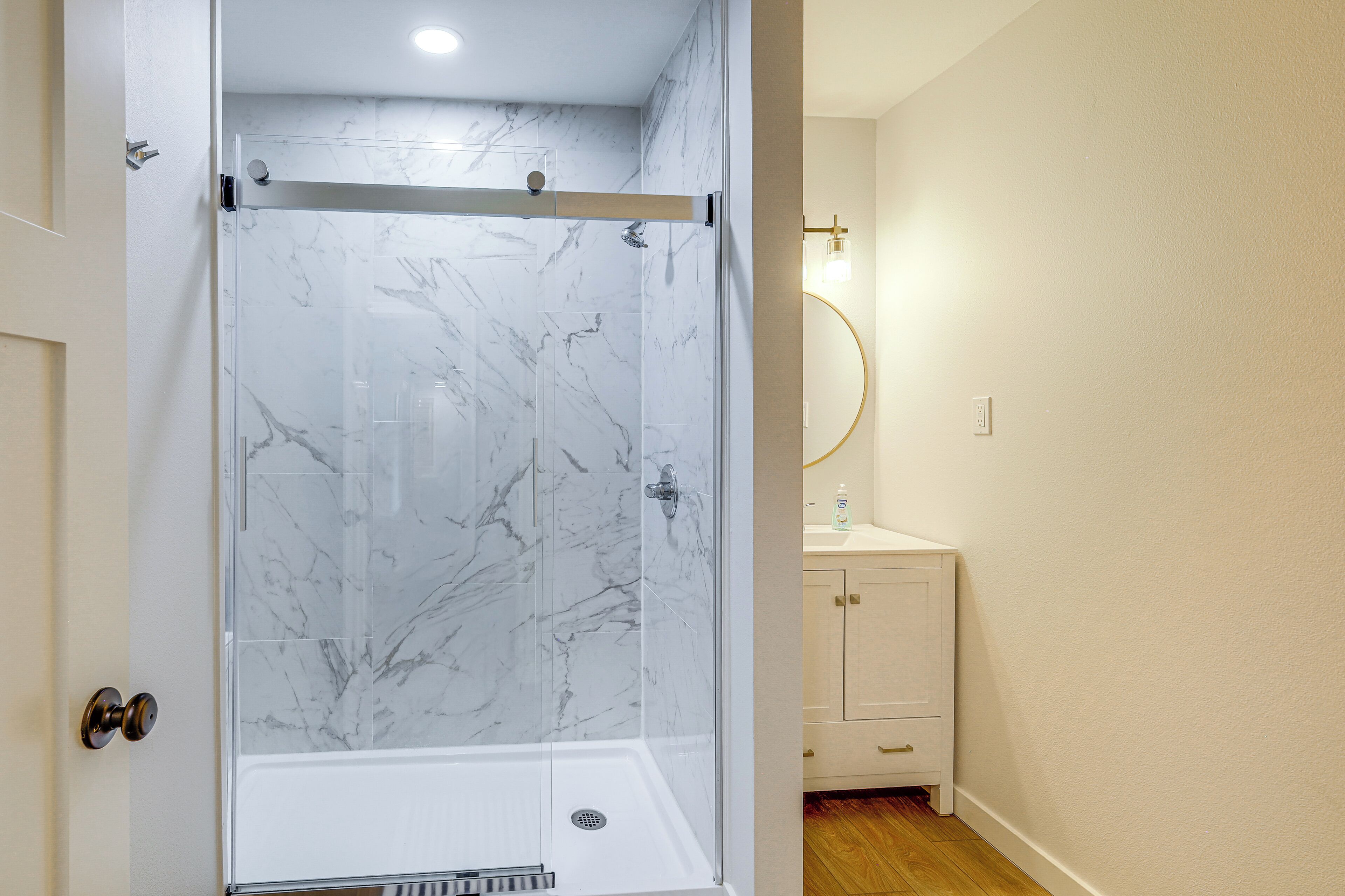 A bathroom with a glass-enclosed shower, a white sink, and a mirror.