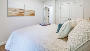 Ein Schlafzimmer mit einem großen Bett, zwei an der Wand befestigten Bildern, einer Tür und einer weißen Decke.
