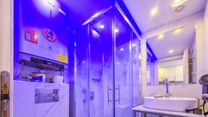 Um banheiro moderno com box de vidro, pia com espelho e porta-toalhas.