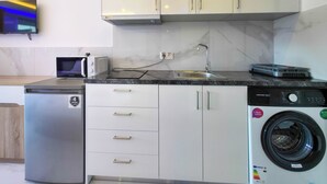 Uma cozinha compacta com máquina de lavar, micro-ondas e pequena geladeira.