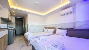 Quarto de hotel com duas camas, uma cozinha compacta e aparelho de ar condicionado.