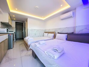 Ein Hotelzimmer mit zwei Betten, einer Küchenzeile und einer Klimaanlage.