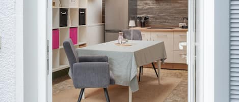 A modern kitchen with a built-in oven, a dining table with chairs, and a chandelier.