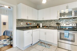 Eine moderne Küche mit weißen Schränken, einem Edelstahlbackofen und einer gefliesten Spritzschutzwand.