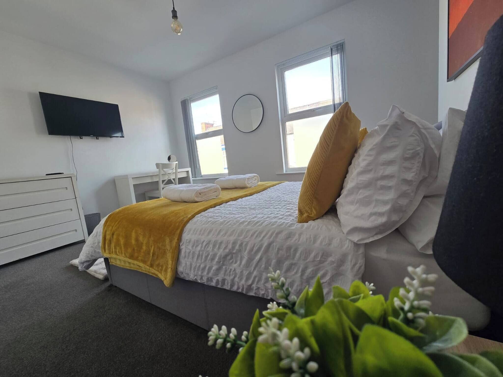 A modern hotel room with a bed, a bedside table, a flat-screen TV, and a window.
