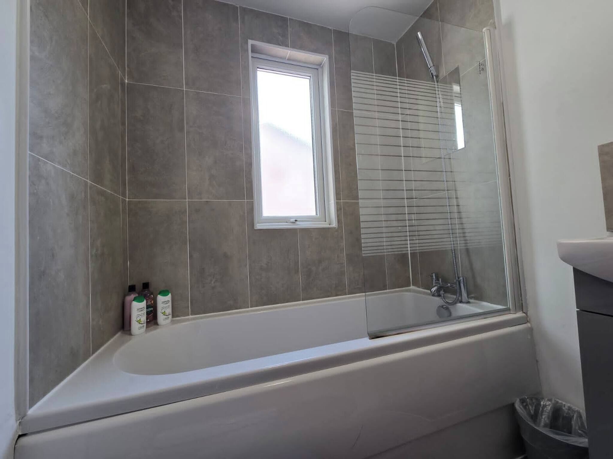 A bathroom with a bathtub, a window, and a shower.
