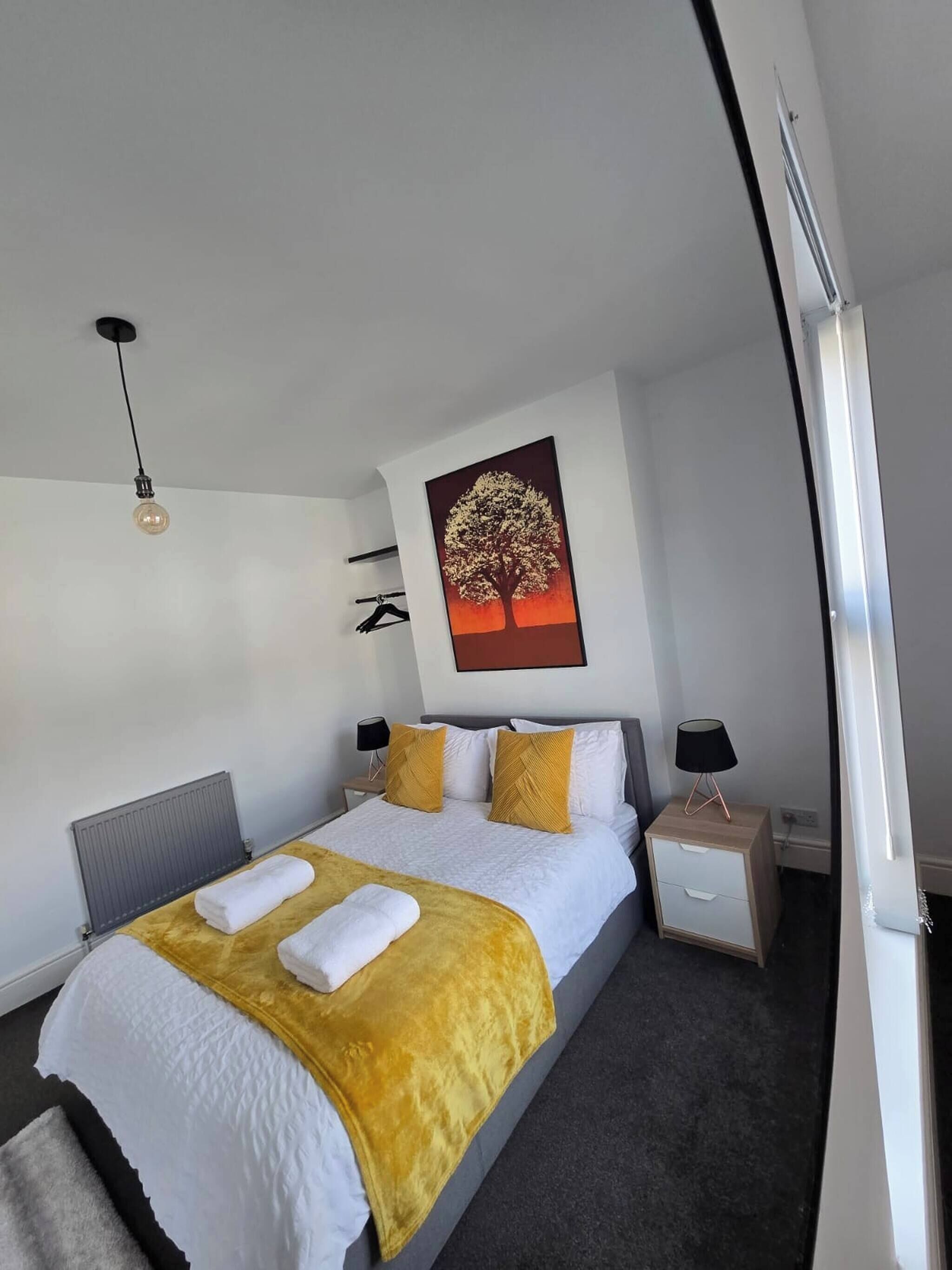 Un dormitorio moderno con una cama grande, una mesita de noche, una lámpara de pared y un aplique de techo.