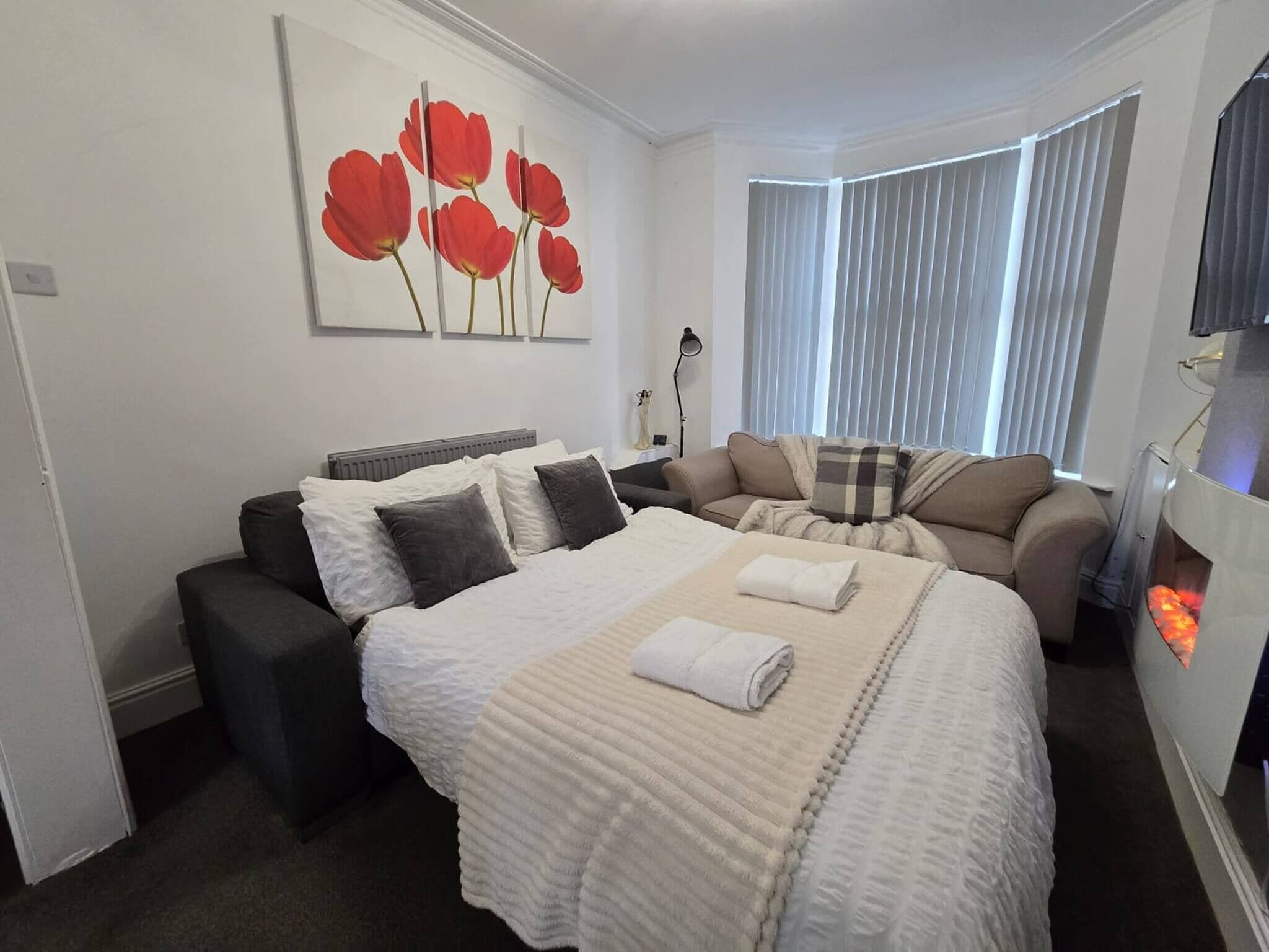 Habitación de hotel con cama, sofá, chimenea y un cuadro en la pared.
