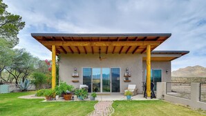 Ein modernes Haus mit überdachter Terrasse, großen Schiebetüren und einem angelegten Garten.