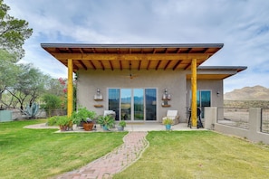 Ein modernes Haus mit überdachter Terrasse, großen Schiebetüren und einem angelegten Garten.