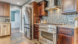 A modern kitchen with stainless steel appliances, wooden cabinets, and a tiled backsplash. - Treehouse Views! Walking Distance to IMS (Indianapolis)
