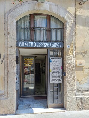 Ein Geschäft mit einem Schild, auf dem 'AlterCAD Copisteria Stampa Digitale' steht, und einer Liste von Dienstleistungen wie Kopiermöglichkeiten und Druckservice.