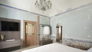 Une chambre à coucher comprenant un lit, une télévision, une armoire, un miroir et un lustre.