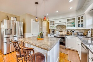 A kitchen with a central island, stainless steel appliances, white cabinetry, and a tiled floor. - Hiking Days, Fireside Nights! Colorado Springs Gem (Colorado Springs)
