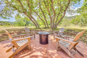 An outdoor seating area with four Adirondack chairs and a round table, surrounded by trees and a clear sky. - Hiking Days, Fireside Nights! Colorado Springs Gem (Colorado Springs)