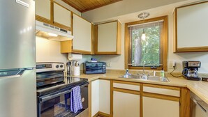 Eine Küche mit Kühlschrank, Backofen, Mikrowelle, Spüle und Holzschränken.