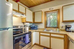 Eine Küche mit Kühlschrank, Backofen, Mikrowelle, Spüle und Holzschränken.