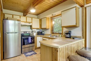 Cocina compacta con refrigerador, horno, microondas y cafetera.