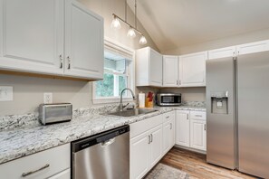 A modern kitchen with white cabinetry, a stainless steel refrigerator, a built-in microwave, and a dishwasher. - Hunt & Fish! Home < 1 Mi to Broad River Campground (Tignall)